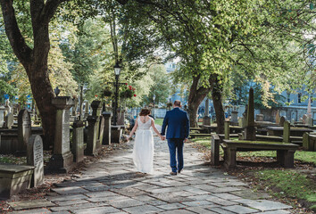 Newly married couple walk away in a cemetary