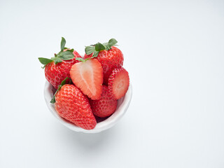 whole and sliced strawberries in a small white bowl
