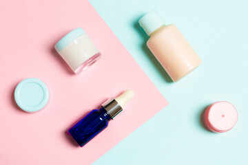 Top view of cosmetic containers, sprays, jars and bottles on pink background. Close-up view with empty space for your design