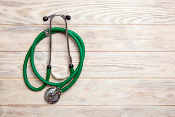Top view of green stethoscope on yellow wooden background. Medical examination concept