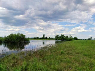 beautiful blue sky with clouds over a green field with a small river