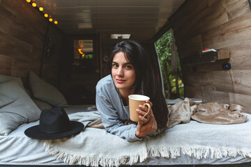 Young girl having coffee in her caravan bed 