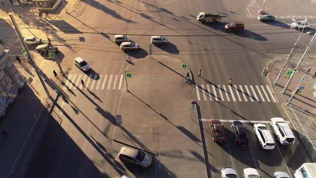 Pedestrian crossing on a city street with traffic density car. High Angle Shot. People walk in a big city in the evening or in the morning. Road zebra marking. Quarantined city.