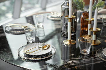 Home Inerior with dining room table setting with gold stainless tableware and cutlery setting on nartual marble top / interior design