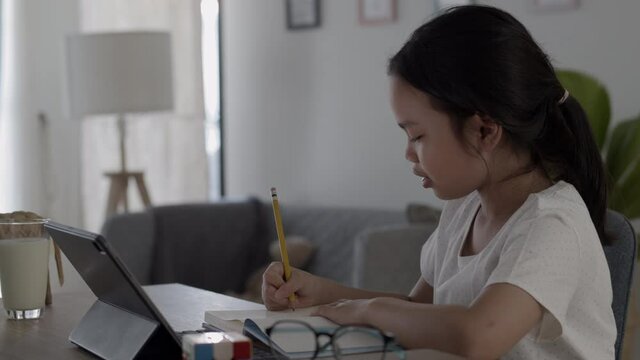 Asian girl doing homework And study online with tablet on desk at night.
