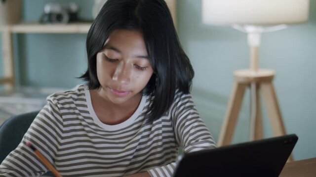  Asian girl doing homework And study online with tablet on desk at night.
