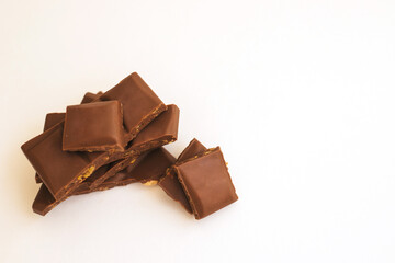 Chocolate slices are stacked on a white background.Dark chocolate with nuts.