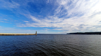 Lighthouse on a calm sea. White clouds in the sky.