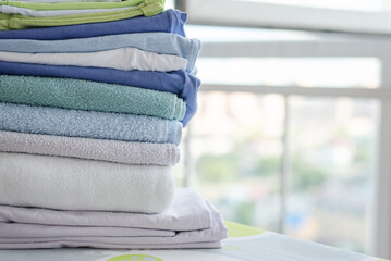 Stack of clean clothes on ironing board close up.