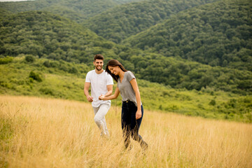 Naklejka premium Happy young couple in love walking through grass field