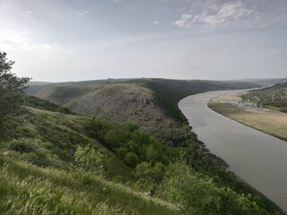 Blue river with yellow reeds. Green mountains.