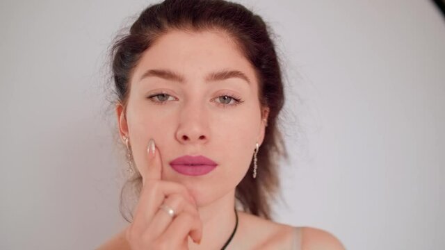 Portrait of young cuacasian brunette with finger on a cheeck. Process of thinking
