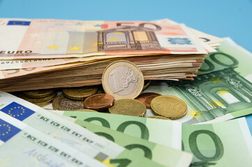 Euro coins and euro banknotes. Blue background. Much money. Savings concept. Financial concept. 1 euro coin. Stack with euro banknotes.