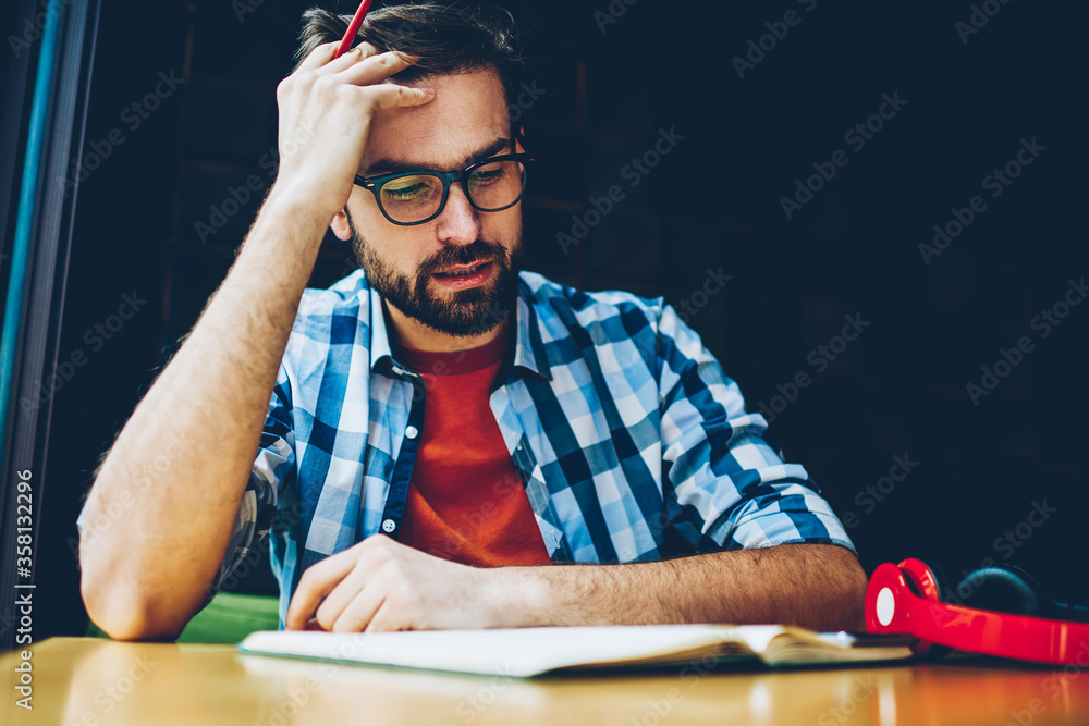 Poster pensive bearded student reading literature book and preparing for upcoming exams.concentrated young 