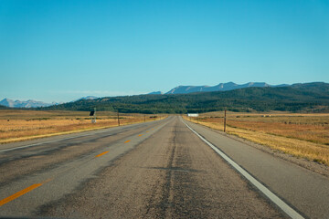 Fototapeta na wymiar Asphalt highway receeding to vanishing point toward mountains