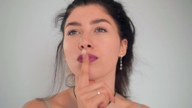 Portrait of young cuacasian brunette with finger on a cheeck. Process of thinking