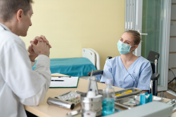 Senior doctor discussing illness with young female patient at hospital