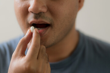 Obraz premium Close up handsome man taking pill. Medicine, health care concept.
