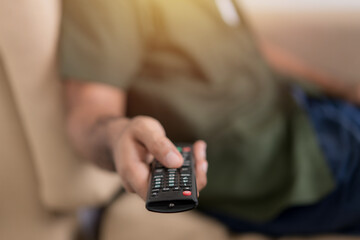 Close up hand holding remote control and watching TV