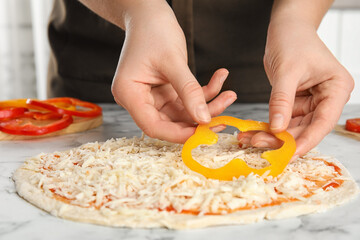 Woman adding bell pepper to pizza white marble table, closeup