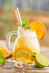 Refreshing jar of orange lemonade with ice, mint, and paper straws