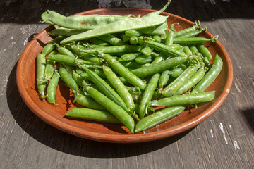 fresh healthy green peas and beans on a clay plate