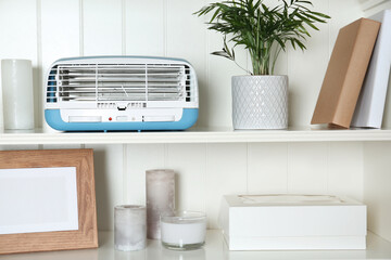 Modern air purifier and different items on white wooden shelves