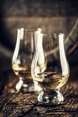Two Glencairn whisky tasting glasses on vintage wood and dark wooden barrel in the back