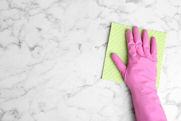 Woman in gloves wiping white marble table with rag, top view. Space for text