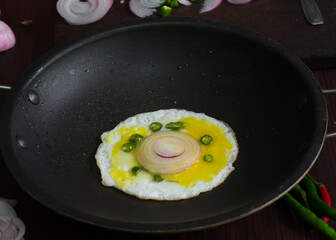 Food, Bulls eye, egg garnished with chilly and onion, looks yummy, tasty. garnished with cutting table, knife and spoon in background.