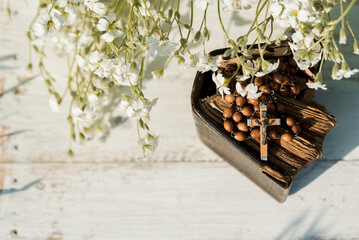 Hands folded in prayer over old Holy Bible. Wooden background.Hands and rosary, prayer, old book with yellow pages. white flowers on a background. in the garden. Concept of prayer and religion
