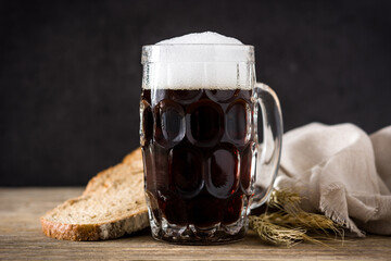 Traditional kvass beer mug with rye bread on wooden table. 	
