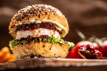 Vegetarian burger with camembert and cranberry sauce on a rustic wooden board