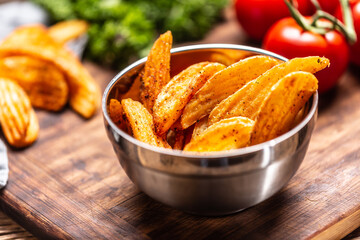 Detail of spiced baked potato wedges in a metal bowl
