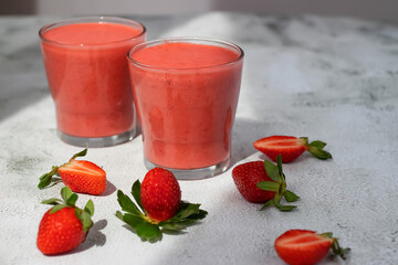 Organic strawberry smoothies in glass cups and ripe strawberries on  gray cement background.