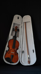 Naklejka premium Violin and its bow in its case, on black background