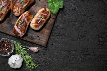 grilled sausages with herbs on the board on a wooden table with copy space
