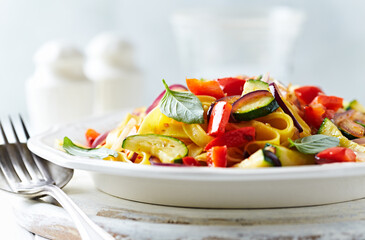 Pappardelle Pasta with Vegetables and fresh Basil on bright wooden Background.