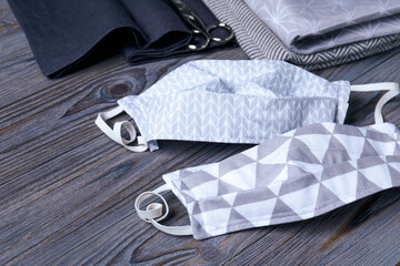 Homemade protective masks, fabric and scissors on wooden background. Sewing idea