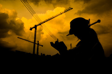 Fototapeta na wymiar Silhouette Asian engineer working at site of a large building project,Thailand people,Work overtime at construction site