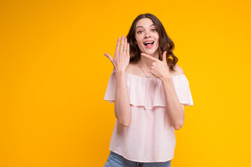 Beautiful excited young brunette woman showing pointing on engagement wedding ring on her...