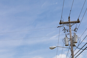 Wooden power pole with mixed power and fiber optics cable wires, street light and transformers...