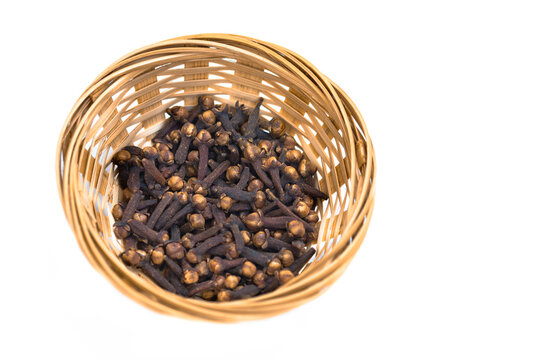 dried cloves in a basket and clear cloves on a white background.