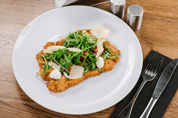A dish of chop meat with arugula and cheese on wooden background