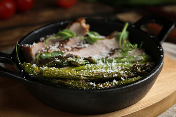 Tasty meat served with asparagus and sprouts in portioned frying pan on table, closeup