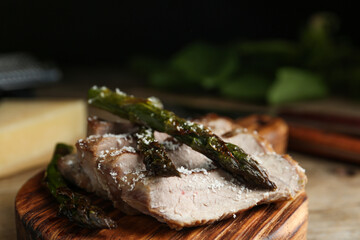 Tasty meat served with asparagus on wooden board, closeup