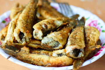 Fried Gobius sobitis (goby fish) on plate View of roasted fish carcasses. Mediterranean cuisine, junk food, tasty snacks for beer concept