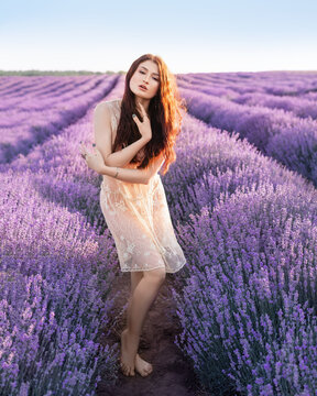 Beautiful girl on the lavender field. Beautiful woman in the lavender field on sunset.Beautiful healthy hair. Young teen girl brunette with long shiny hair over lavender field in Provence. 