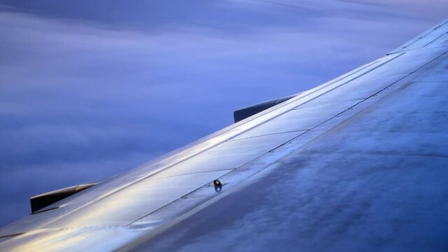flying airplane white wing winglet against breathtaking morning sky view of tender blue and pink colors extreme closeup. Concept airplane travel