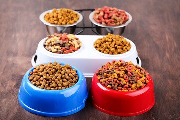 Dry pet food in bowls on brown wooden table